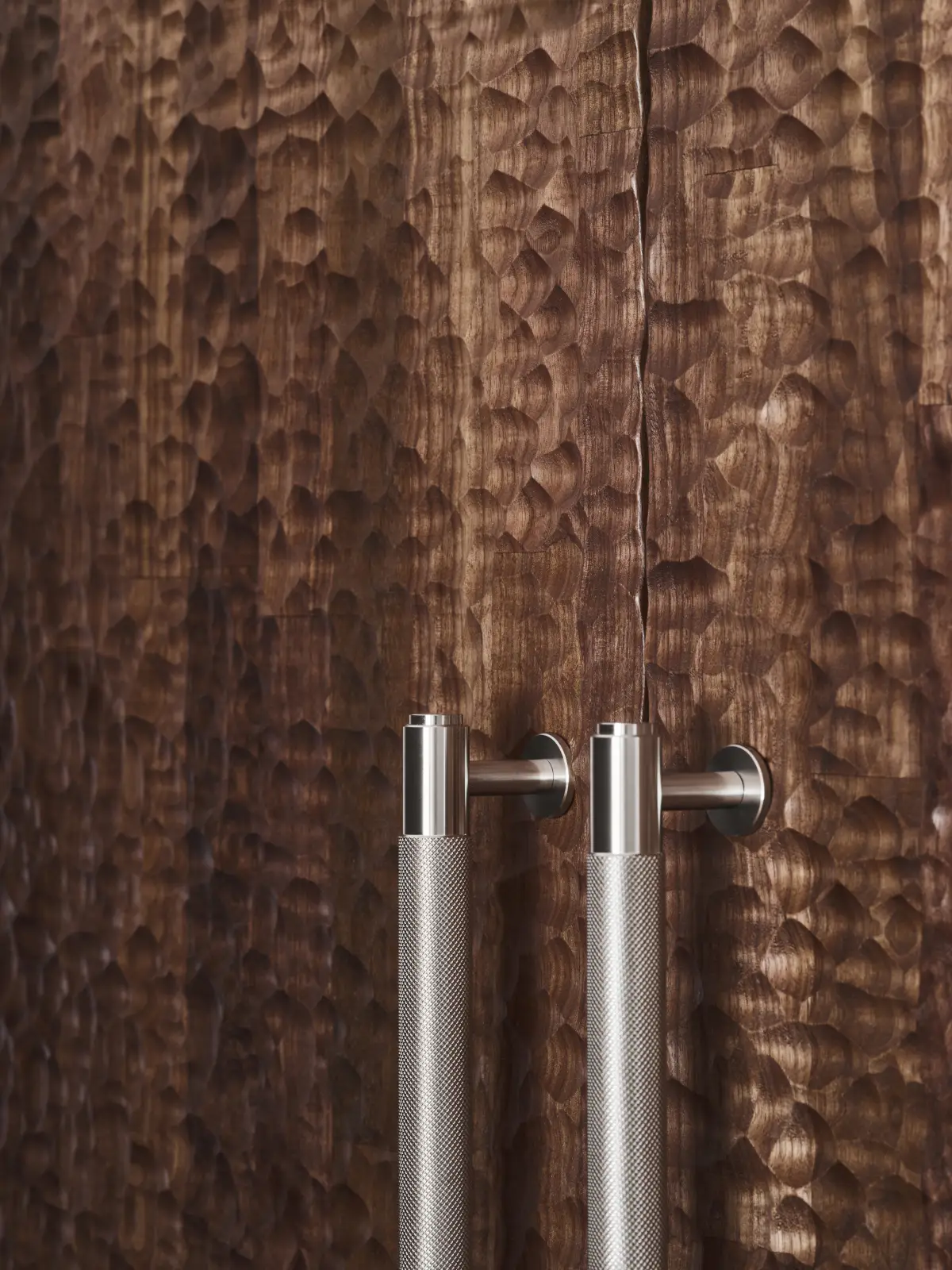 Poignée métallique, couleur acier, sur porte de placard en bois foncé à la surface martelée. Une tendance pour donne une seconde vie à son placard