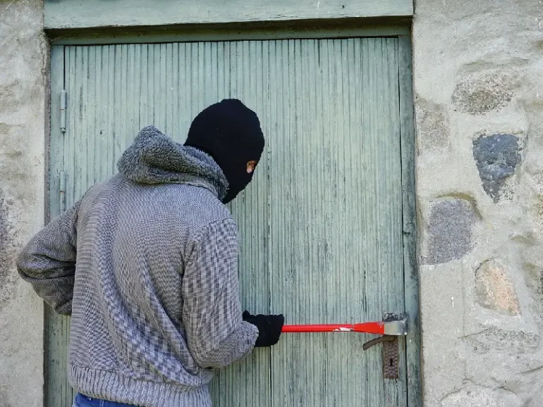 Éviter les cambriolages pendant les vacances d'été, cambrioleur force une porte de maison