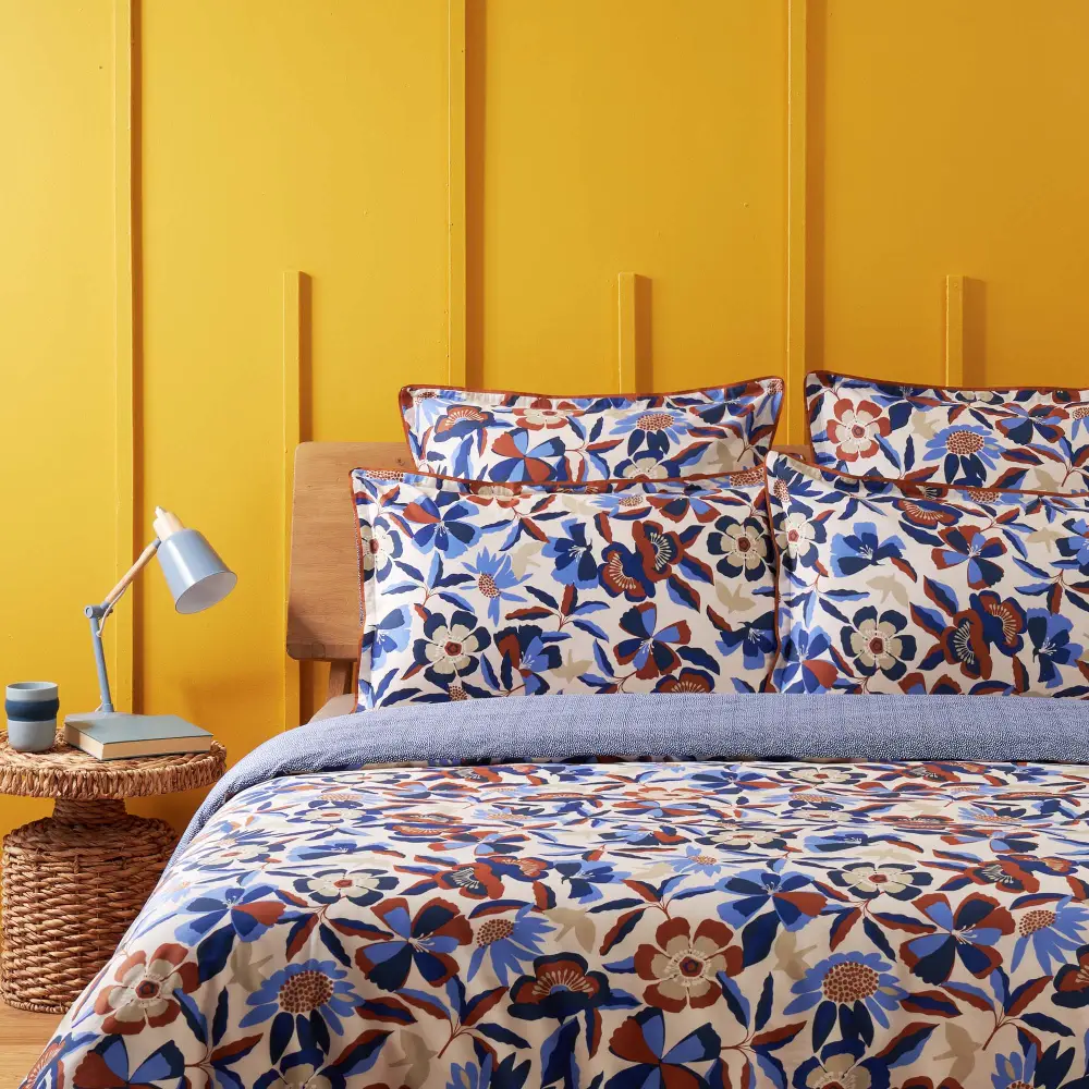 Détail chambre mur jaune avec parure de lit à motifs tons bleu