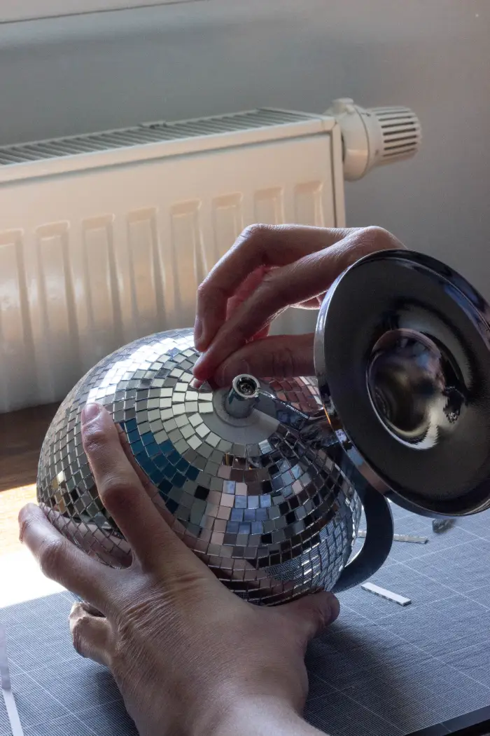 Coller les derniers carreaux de mosaïques miroirs sur la seconde extrémité de la mappemonde