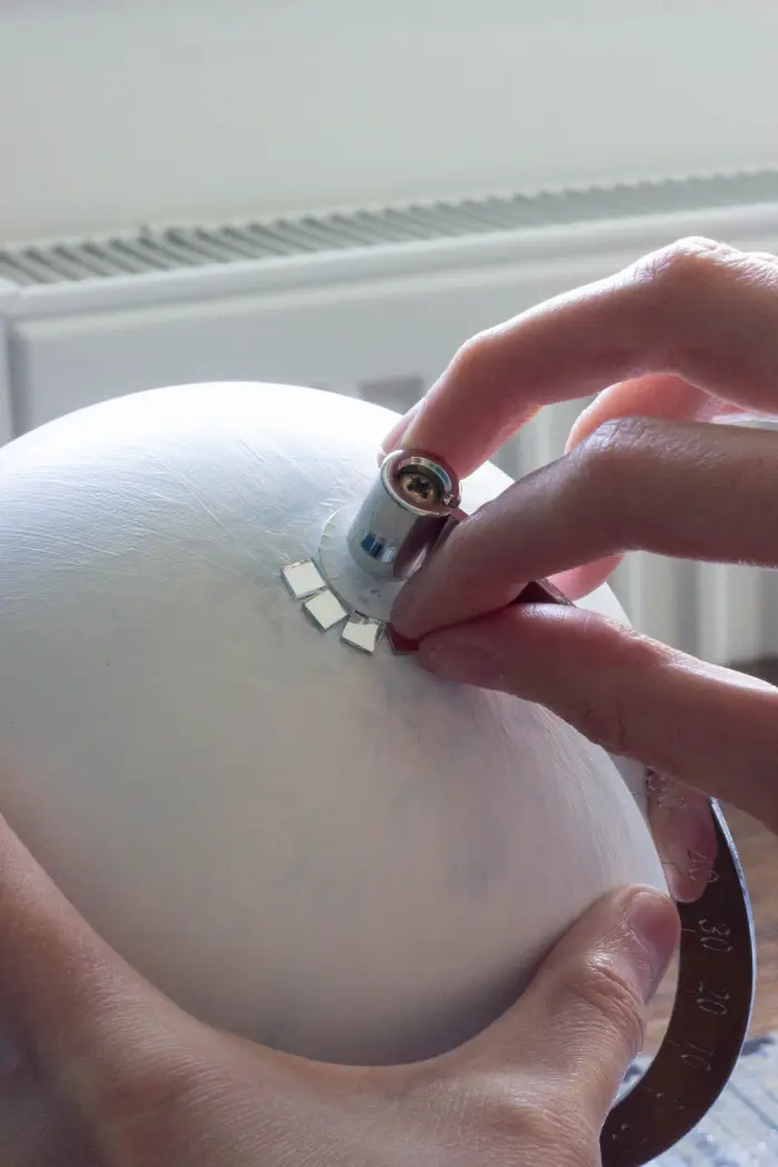 Coller carreaux de mosaïques miroirs un à un sur l'extrémité supérieure du globe terrestre