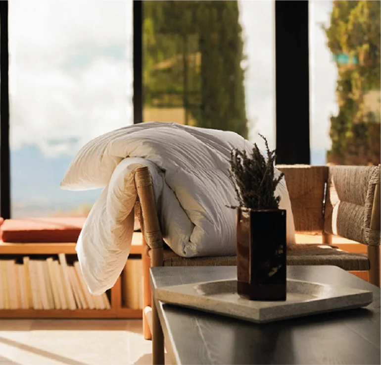 Couette blanche pliée sur le dossier d'une chaise en bois