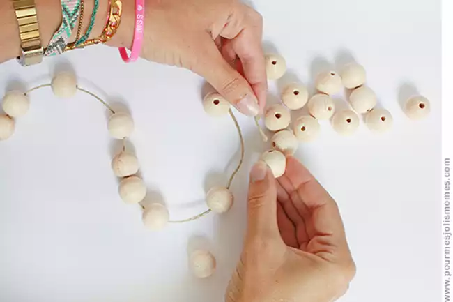 Enfiler des perles en bois sur une ficelle