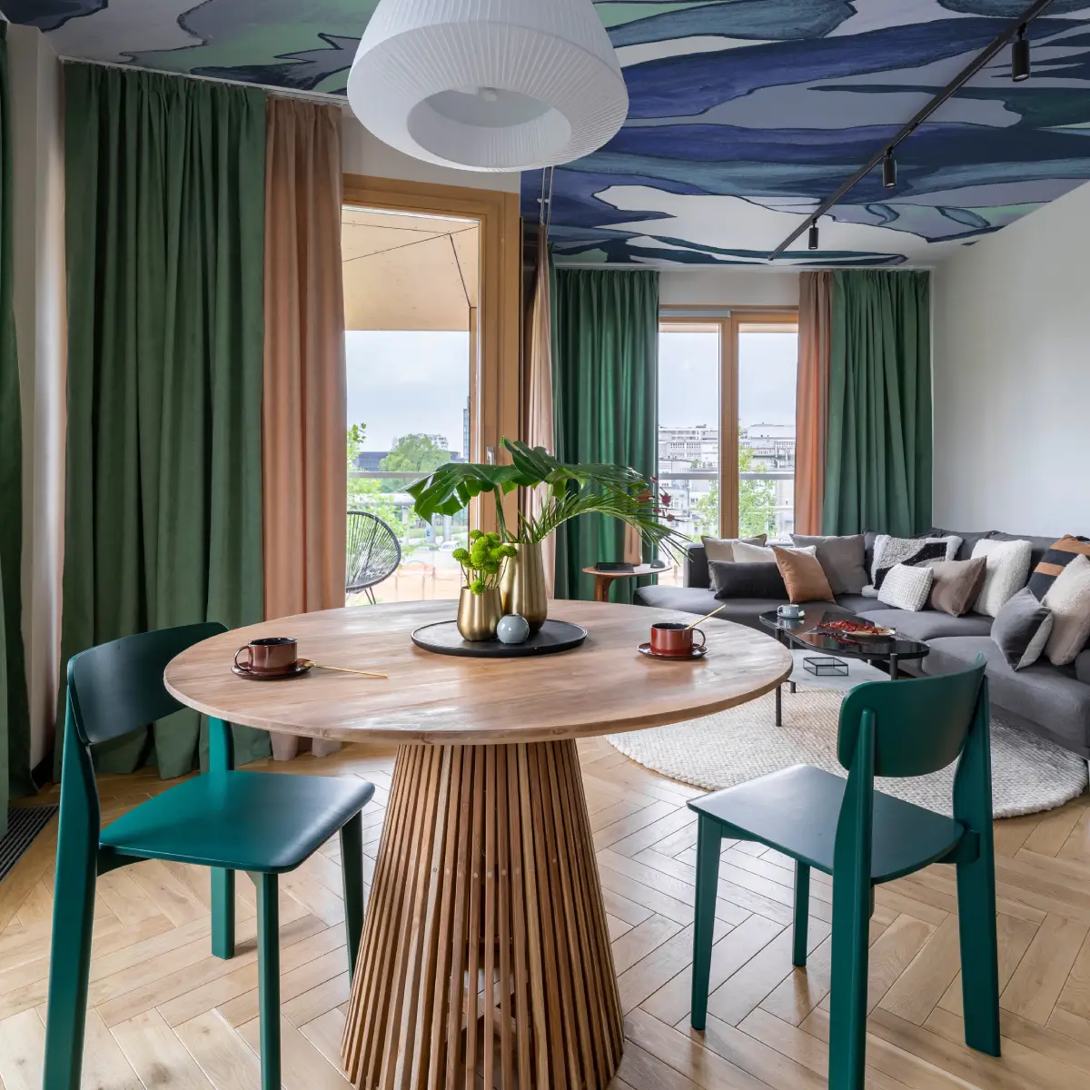 Salon avec chaises et rideaux verts, papier peint motif bleu au plafond