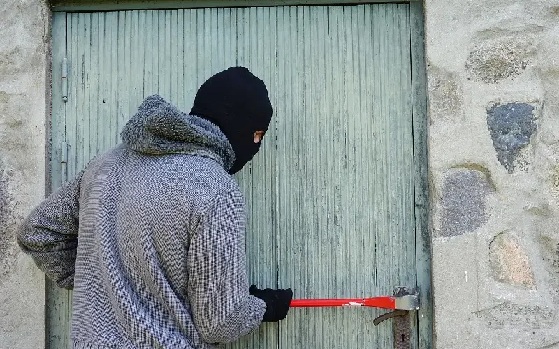 Éviter les cambriolages pendant les vacances d'été, cambrioleur force une porte de maison