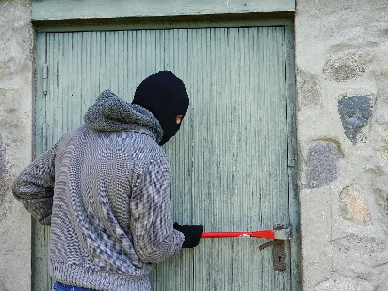 Éviter les cambriolages pendant les vacances d'été, cambrioleur force une porte de maison