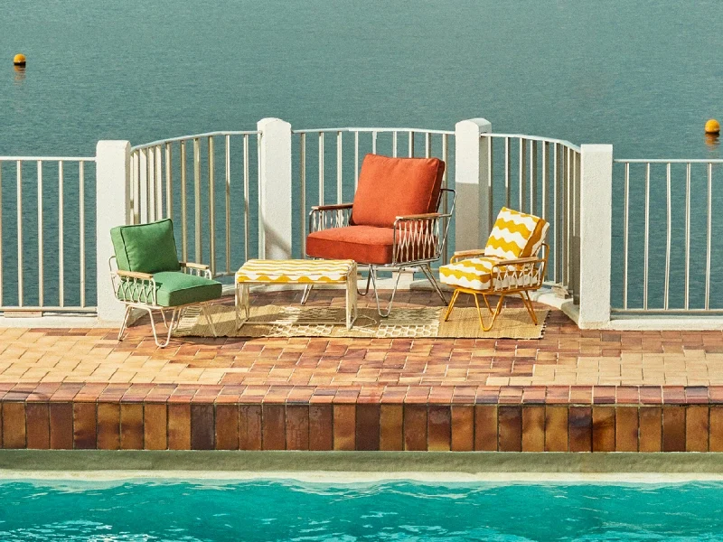 Collection Honoré x Monoprix 2025, fauteuils et table au bord de la mer, inspiration méditerranée