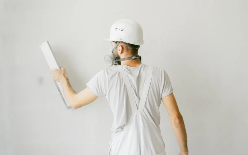 Homme en train d'enduire un mur blanc