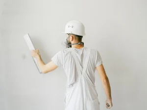 Homme en train d'enduire un mur blanc