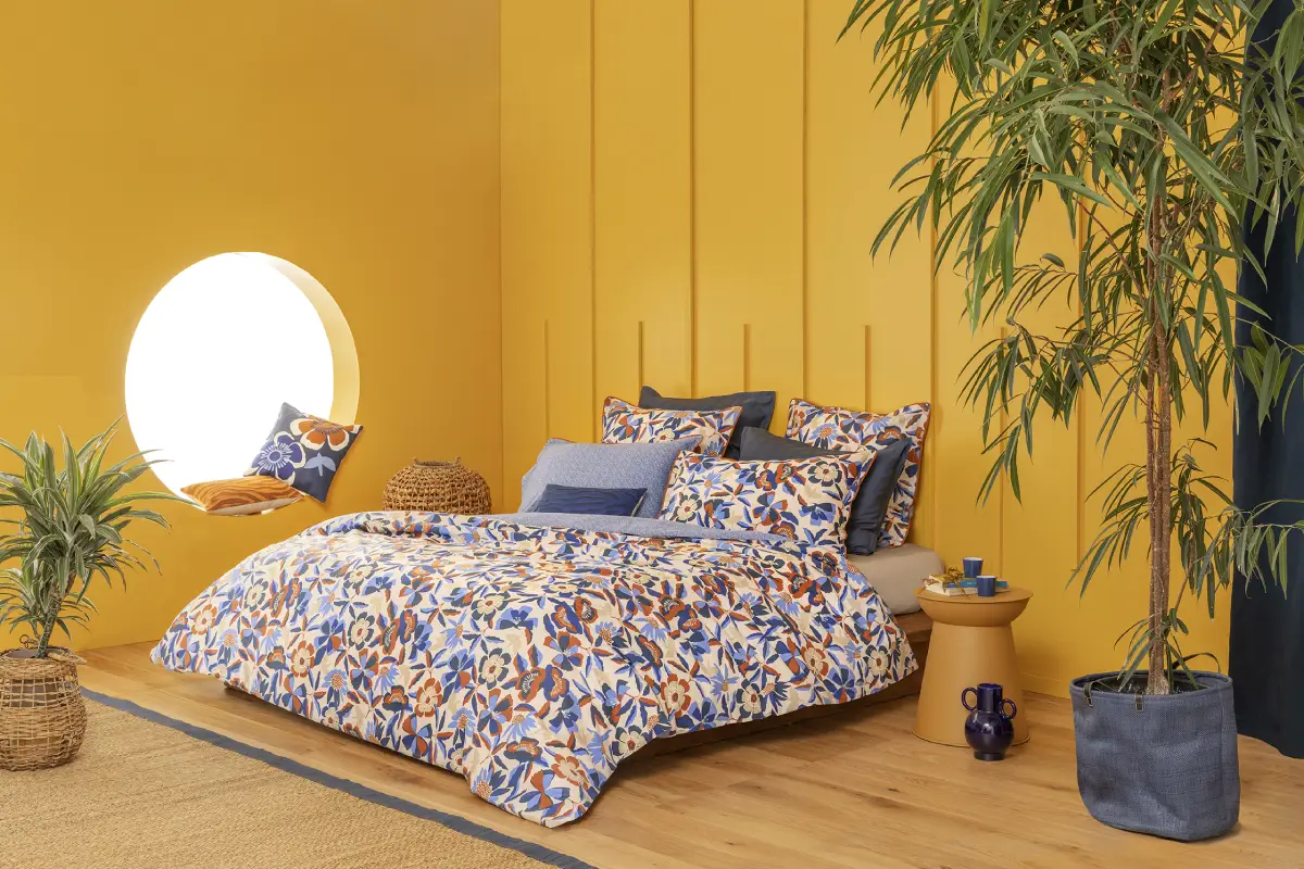 Housse de couette motif floral dans les tons bleu et marron dans une pièce de nuit jaune