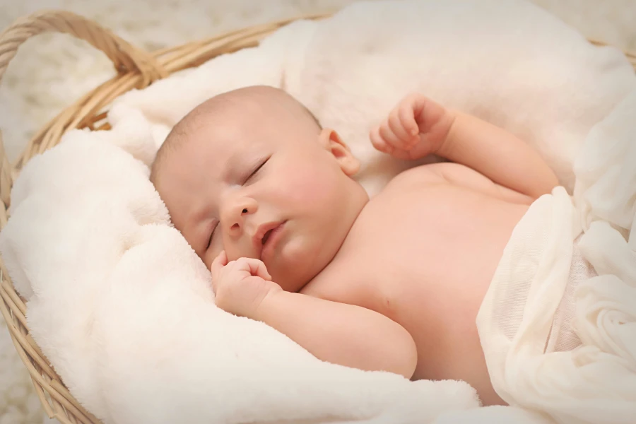 Bébé dans un plaid blanc dans un panier en train de dormir
