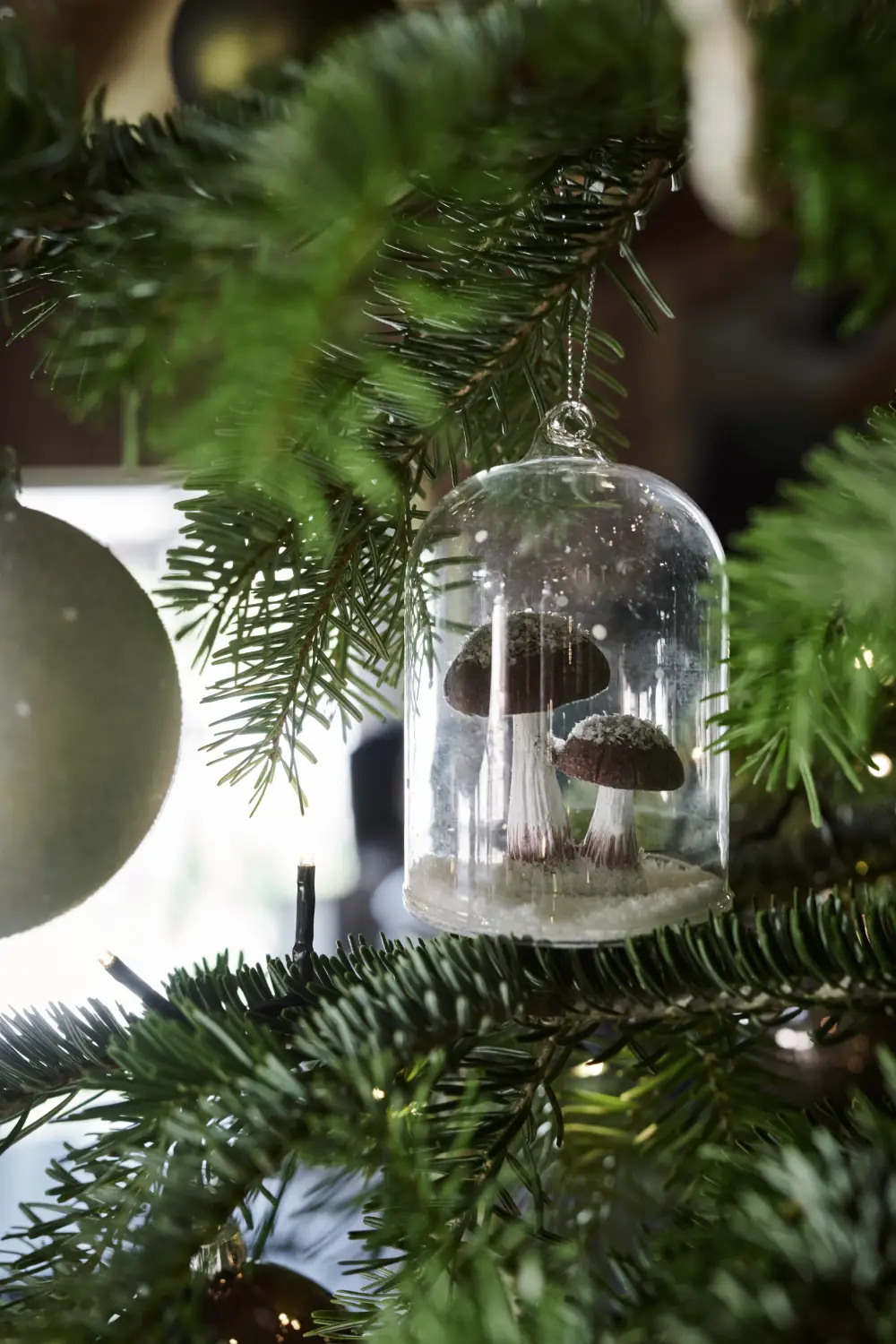 Cloche en verre avec des champignons enneigés à suspendre dans le sapin