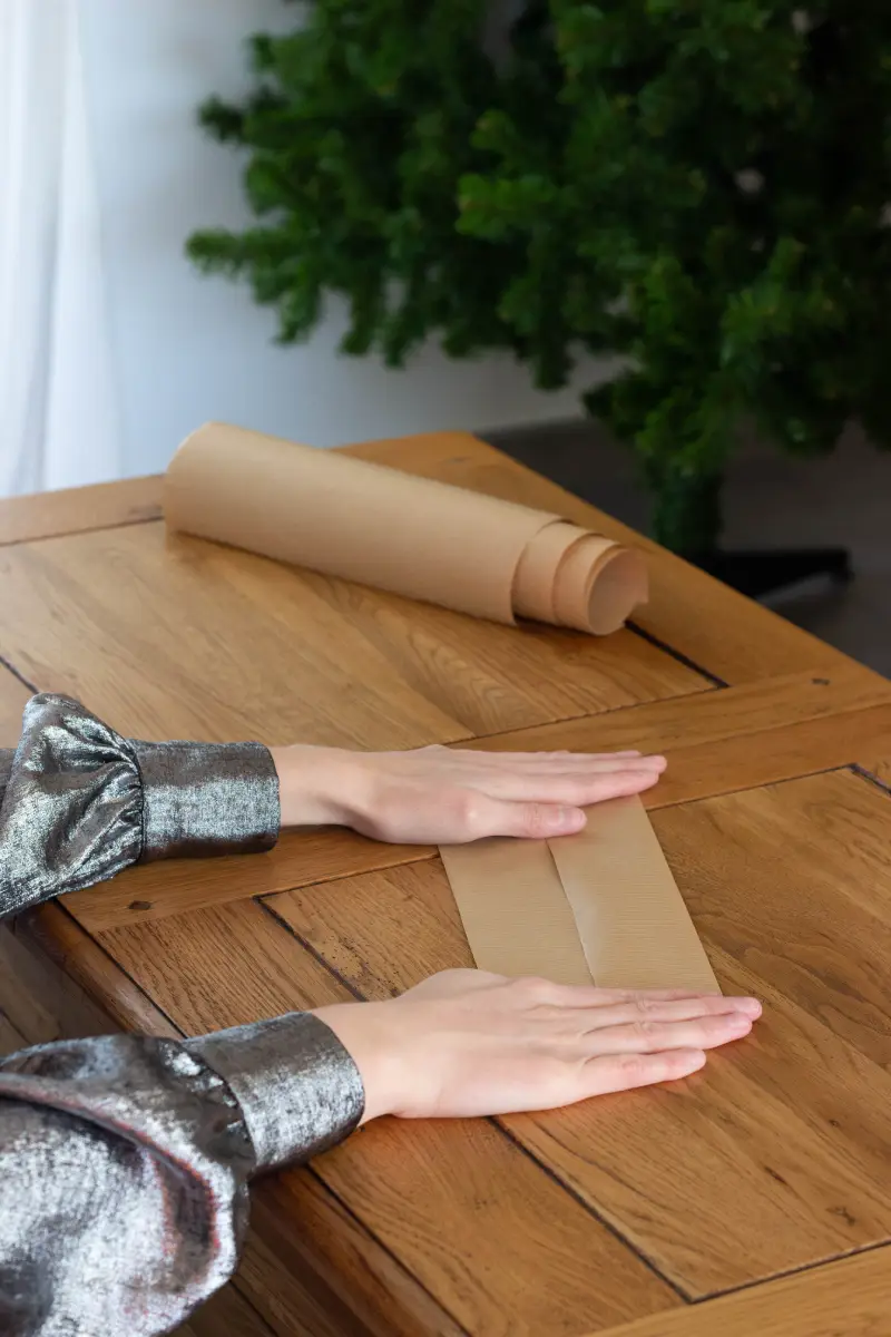 Rabattre la première extrémité dans la longueur au centre de la bande de papier kraft