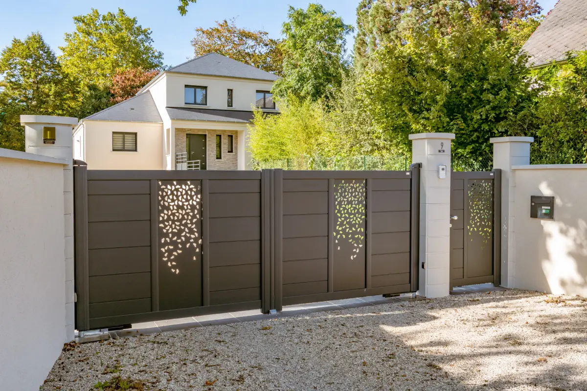 Portail en métal gris foncé, motif ajouré, entrée de la maison