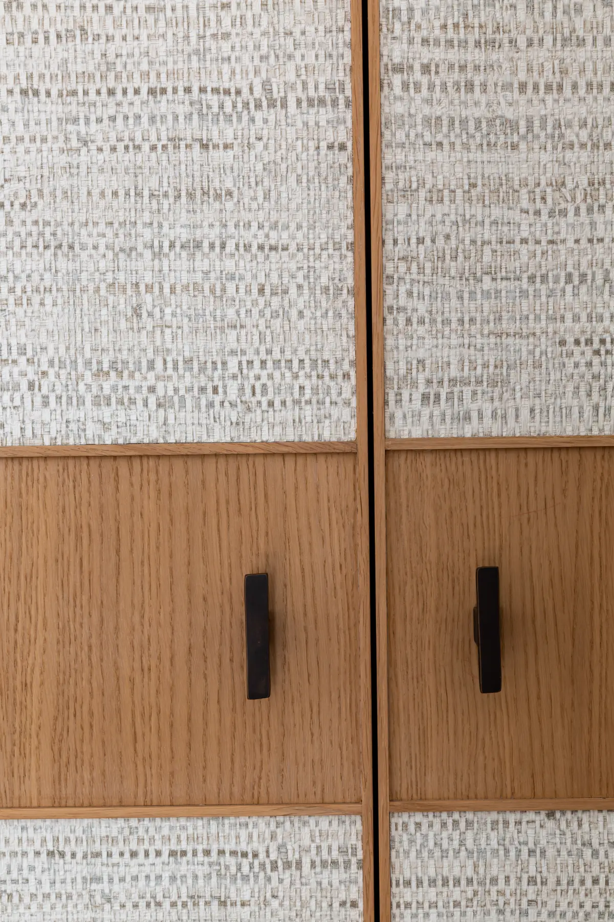 Poignée noire, minimaliste sur porte de placard en bois et revêtement esprit papier peint.