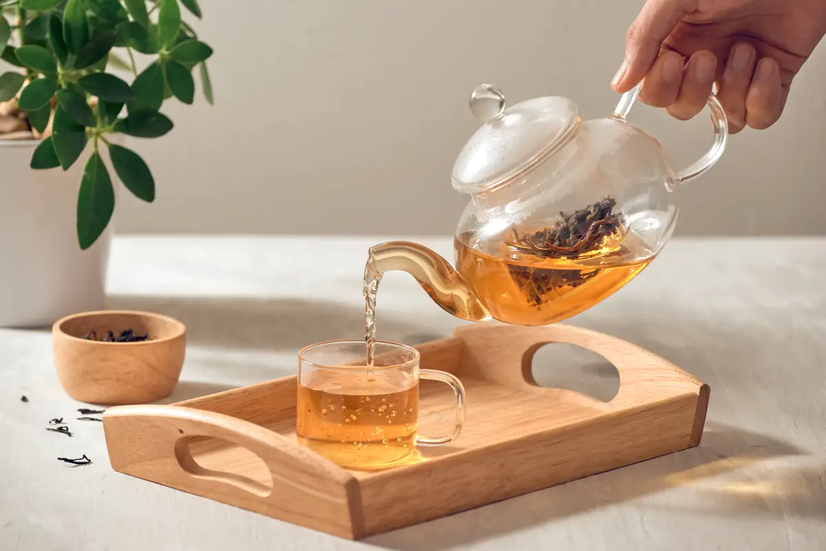 Versement du thé d'une théière dans une tasse transparente