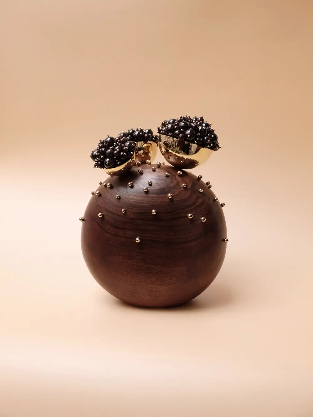 Boule de bois foncé avec bijoux perles et ornements dorés. Salomé Cousseau, artisanat d'art