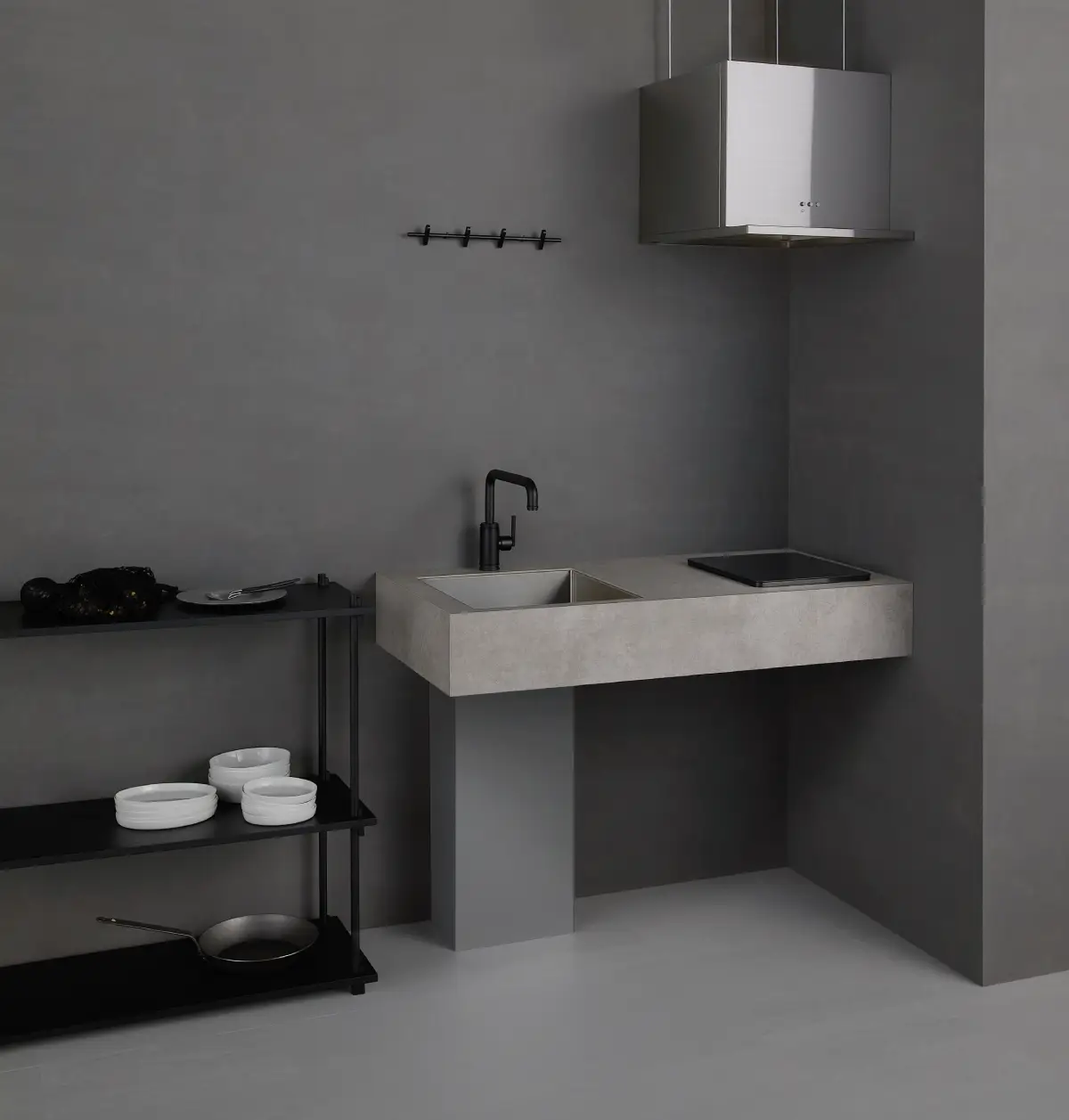 Kitchenette minimaliste avec un évier, une plaque, une hotte et un espace prévu pour le frigo.