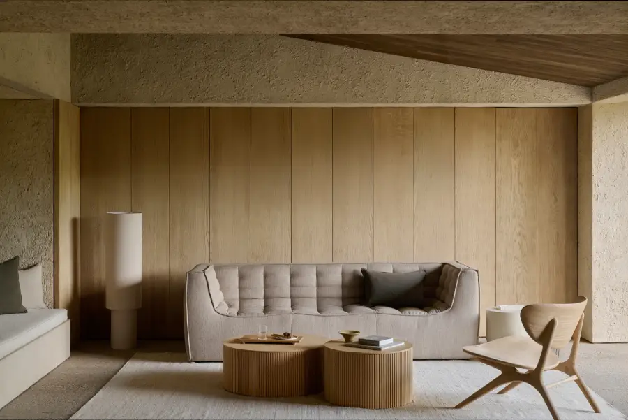 Deux tables basses rondes en bois devant un canapé et mur bois