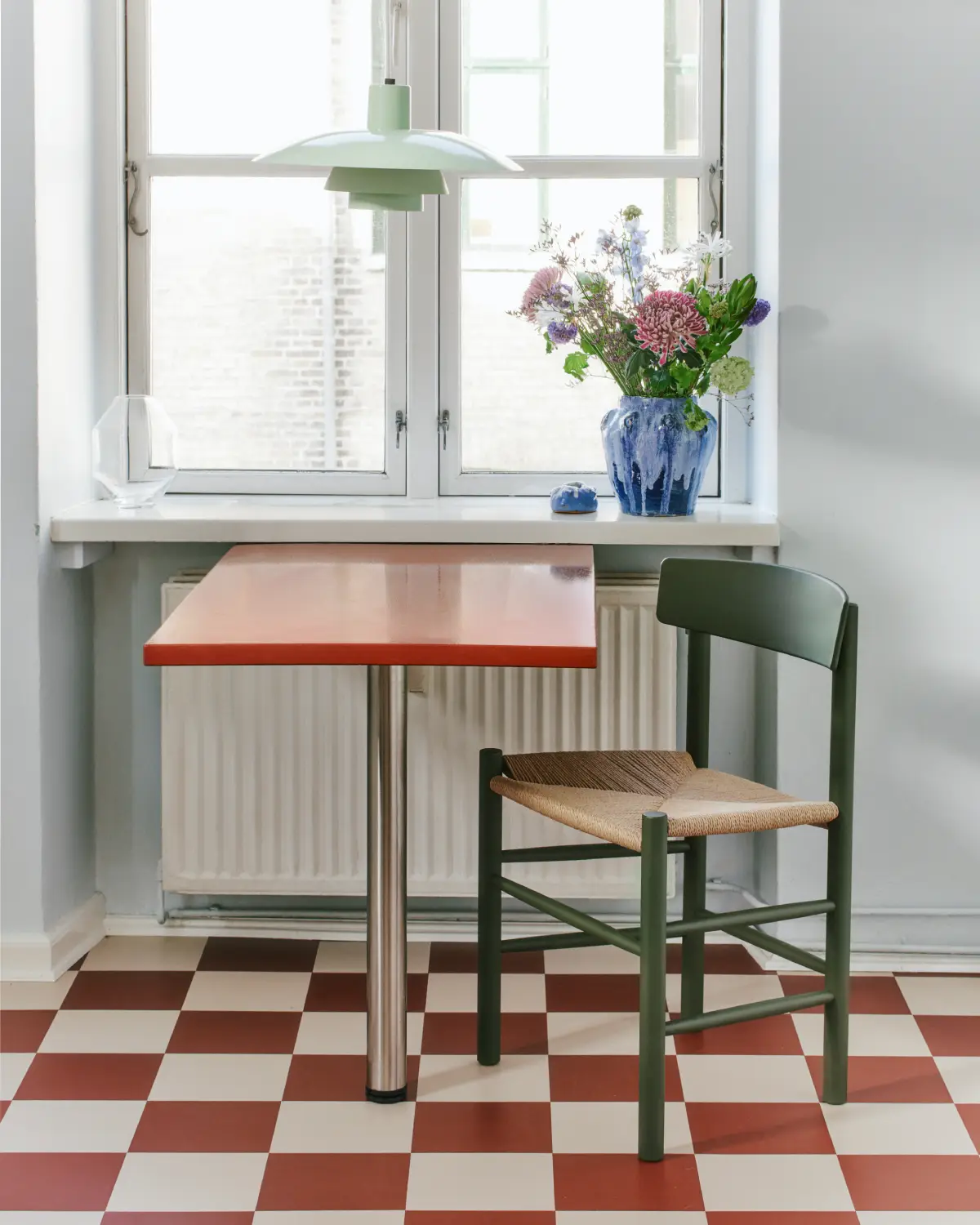 Table de cuisine laquée rouge disposée devant un radiateur pour le camoufler