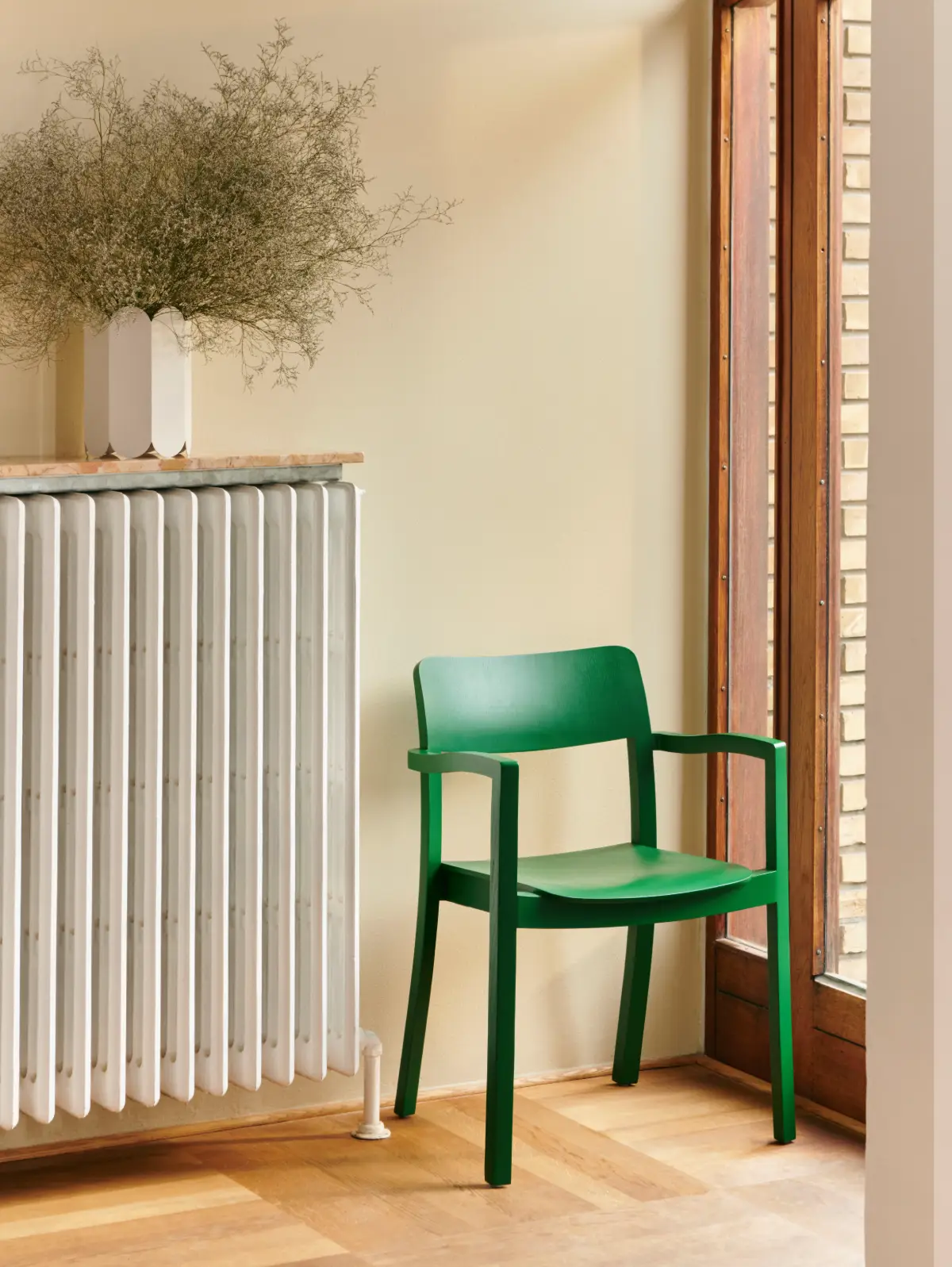 Tablette effet marbre posée sur le radiateur avec un vase blanc dessus et une chaise verte à côté