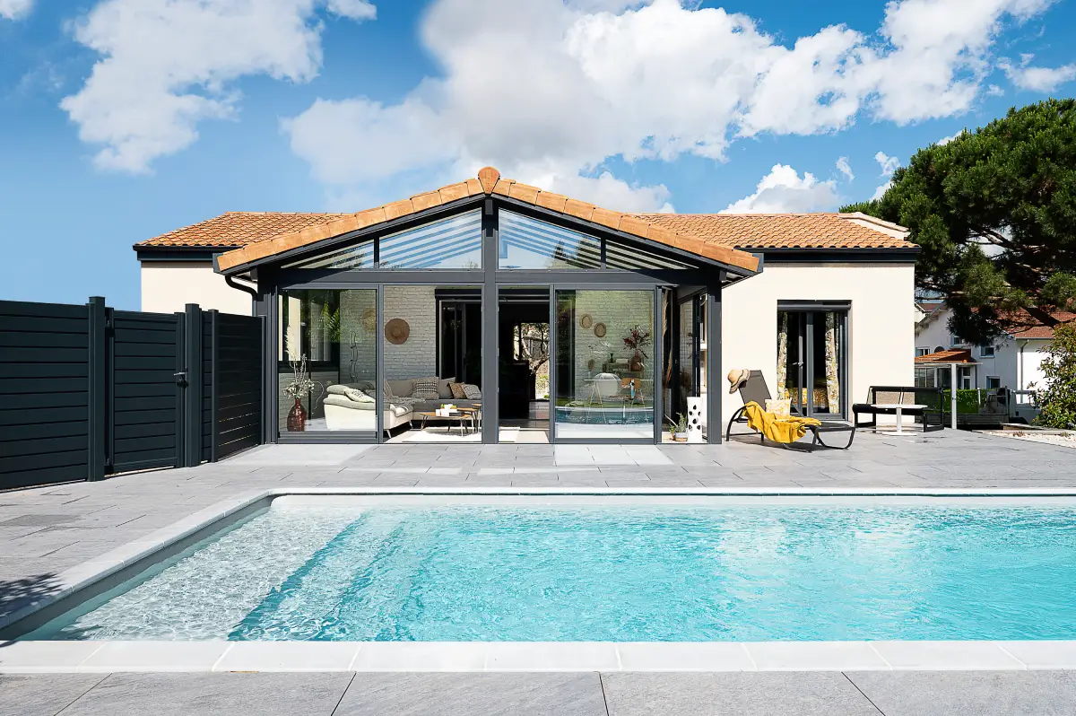 Véranda espace salon avec vue sur la piscine rectangulaire et la terrasse